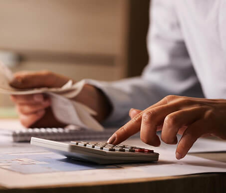 Close nas mãos de um economista usando uma calculadora enquanto segura um boleto