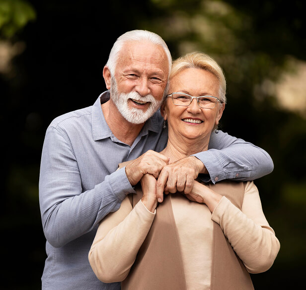Um casal de idosos posando abraçados para a foto sorrindo
