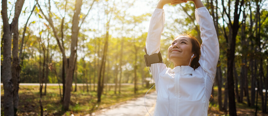 Uma jovem mulher alongando os braços antes de correr no parque