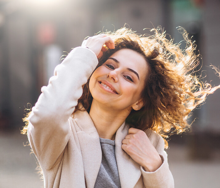 Mulher com cabelos cacheados andando com um casado de outono