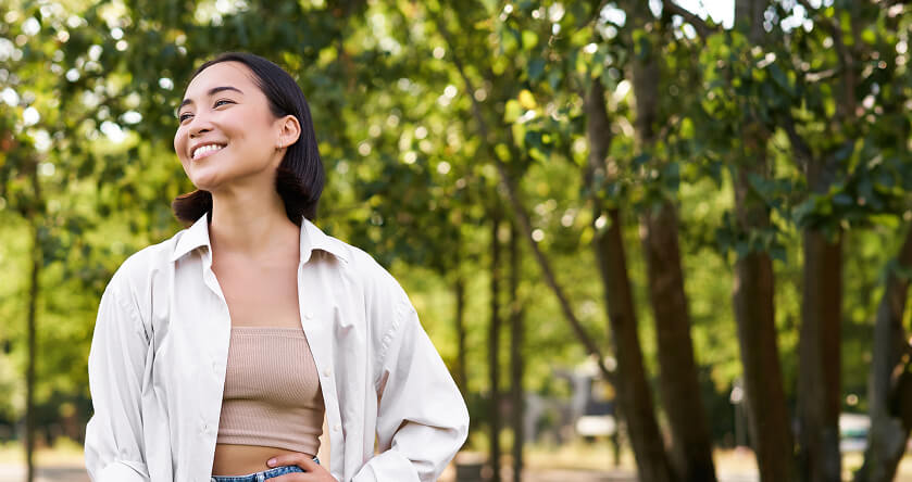 Mulher sorrindo olhando para o horizonte em uma praça